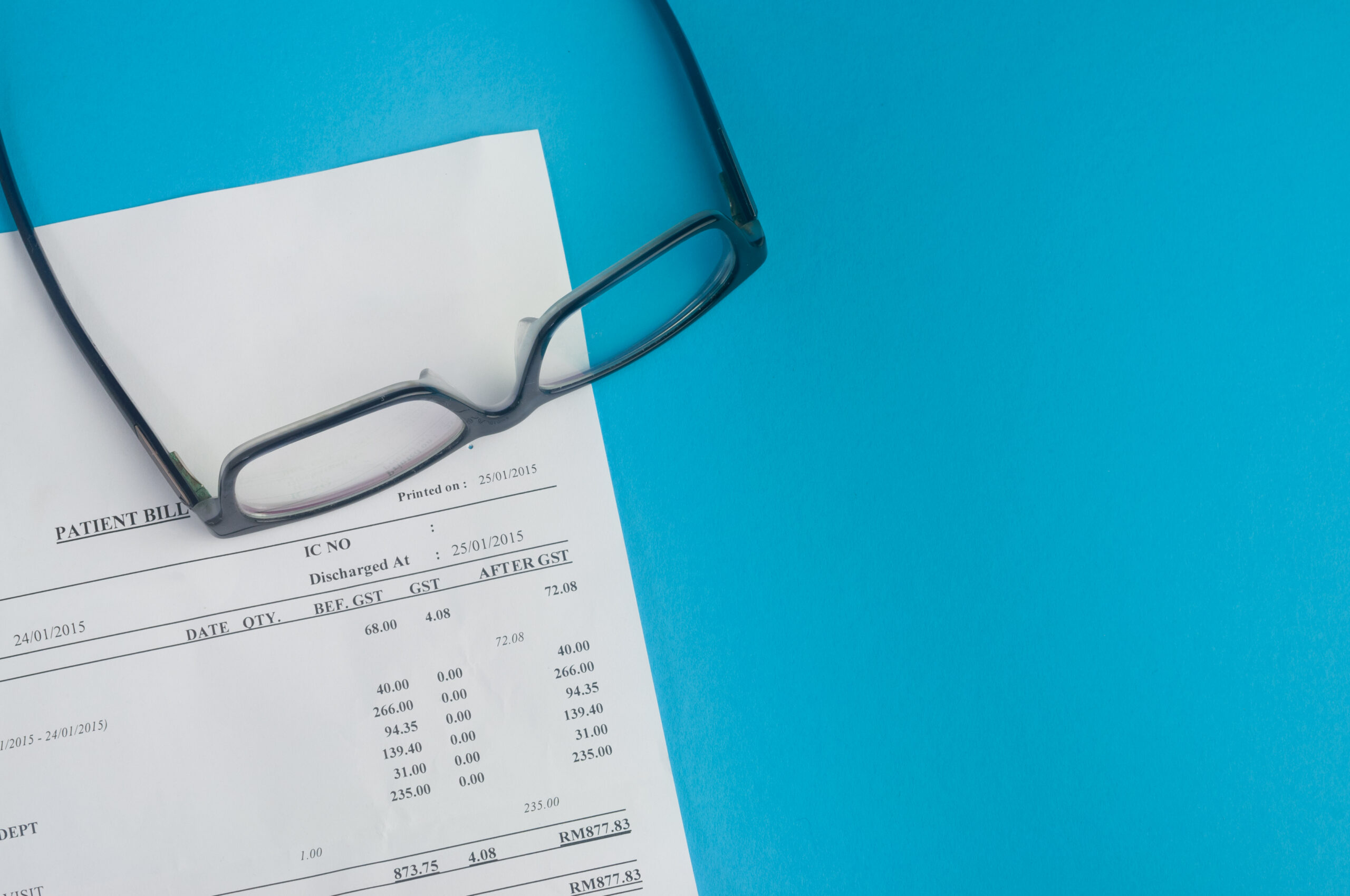 Healthcare Affordability Crisis - Reading glasses resting on an itemized hospital patient bill
